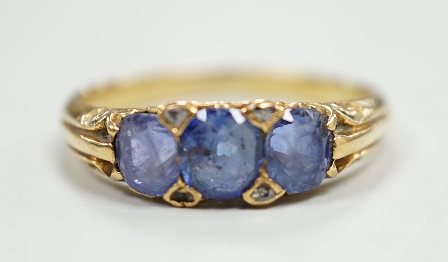 An early 20th century 18ct and three stone sapphire set half hoop ring, with diamond chip spacers, size Q, gross weight 4.2 grams.